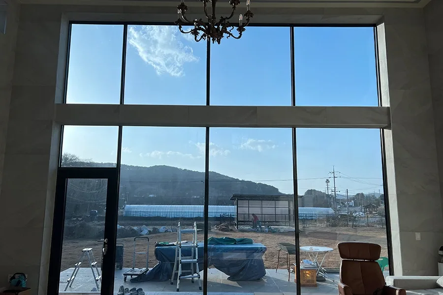 안양 전원주택 실내 계단실 상부에서 바라본 높은 통창과 샹들리에