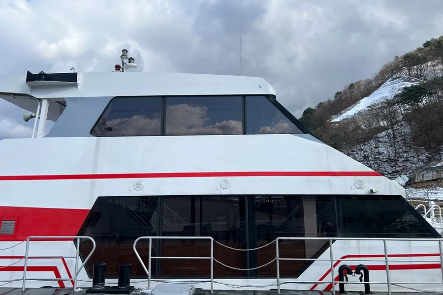 선체 측면에서 바라본 조타실 창문, 짙게 코팅된 유리와 눈 덮인 산비탈 배경